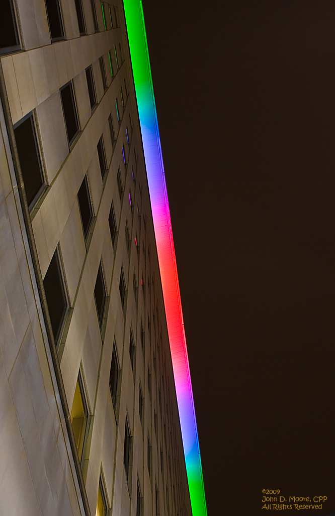 Looking directly up along the wall of the Lincoln Building, toward the rooftop colorful lighting display.