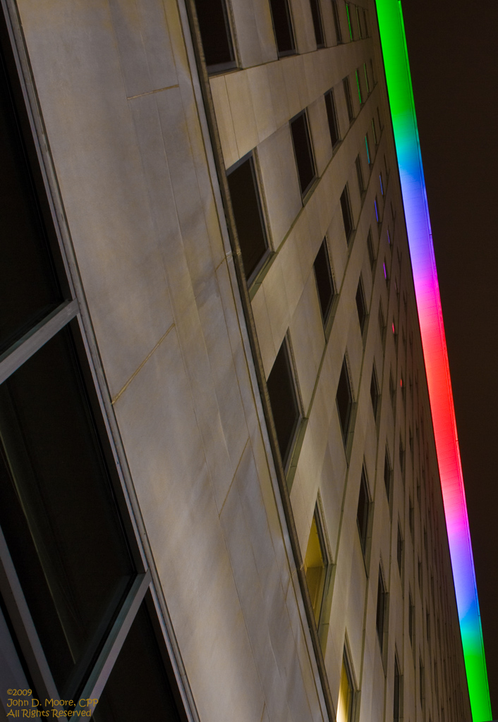 Looking directly up along the wall of the Lincoln Building, toward the rooftop colorful lighting display.